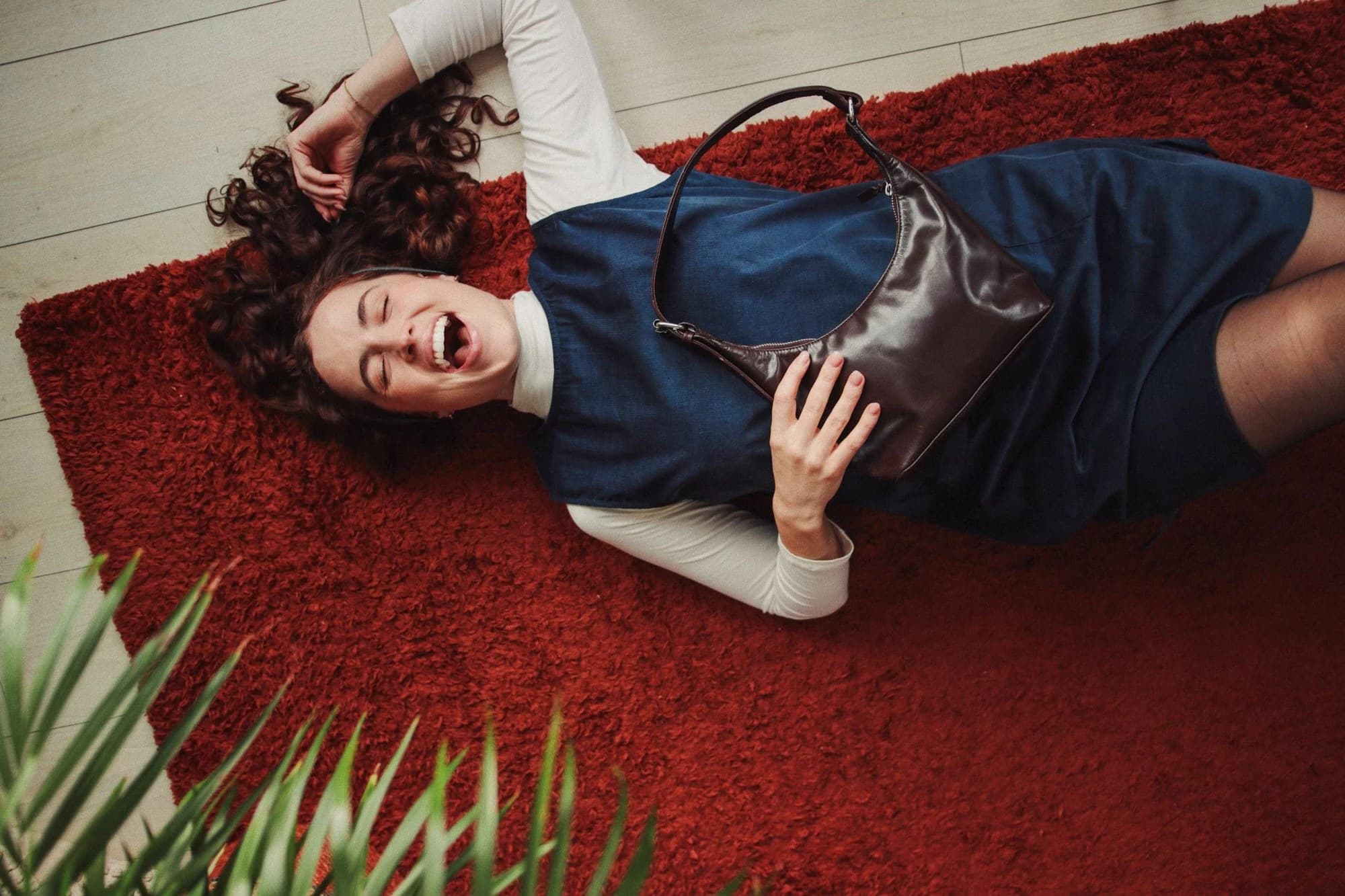 Maili corduroy pinafore and leather bag, worn on a red rug